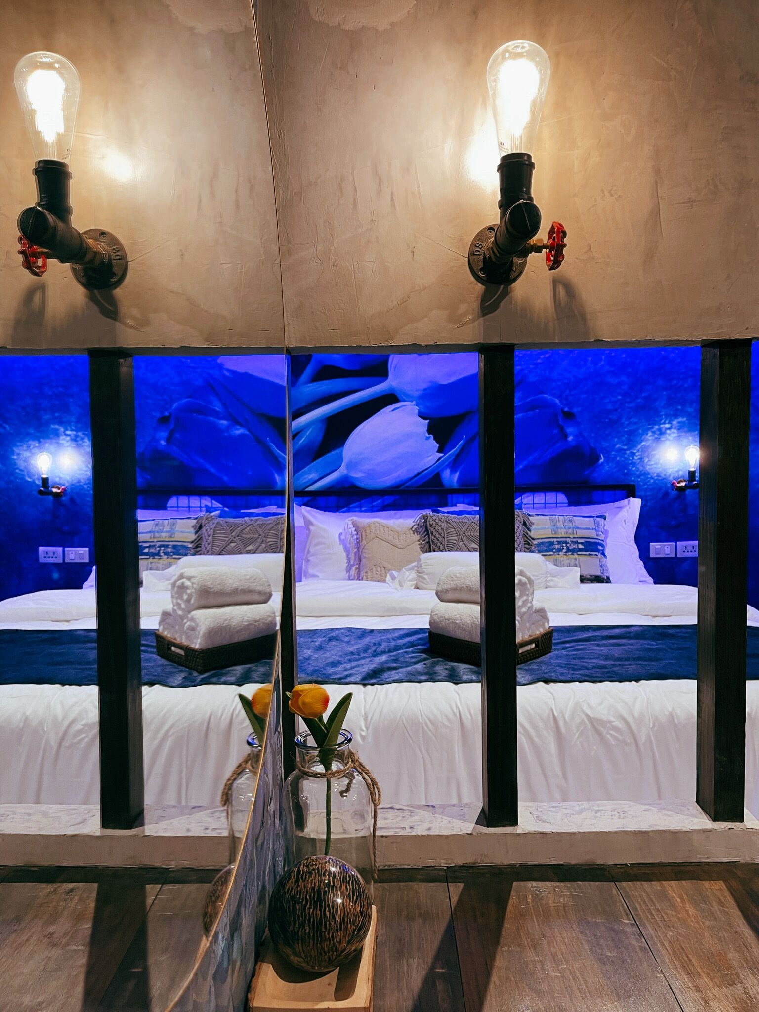 A room with a bed, towels, a vase with flowers, and a view of an ice cave through a large window.