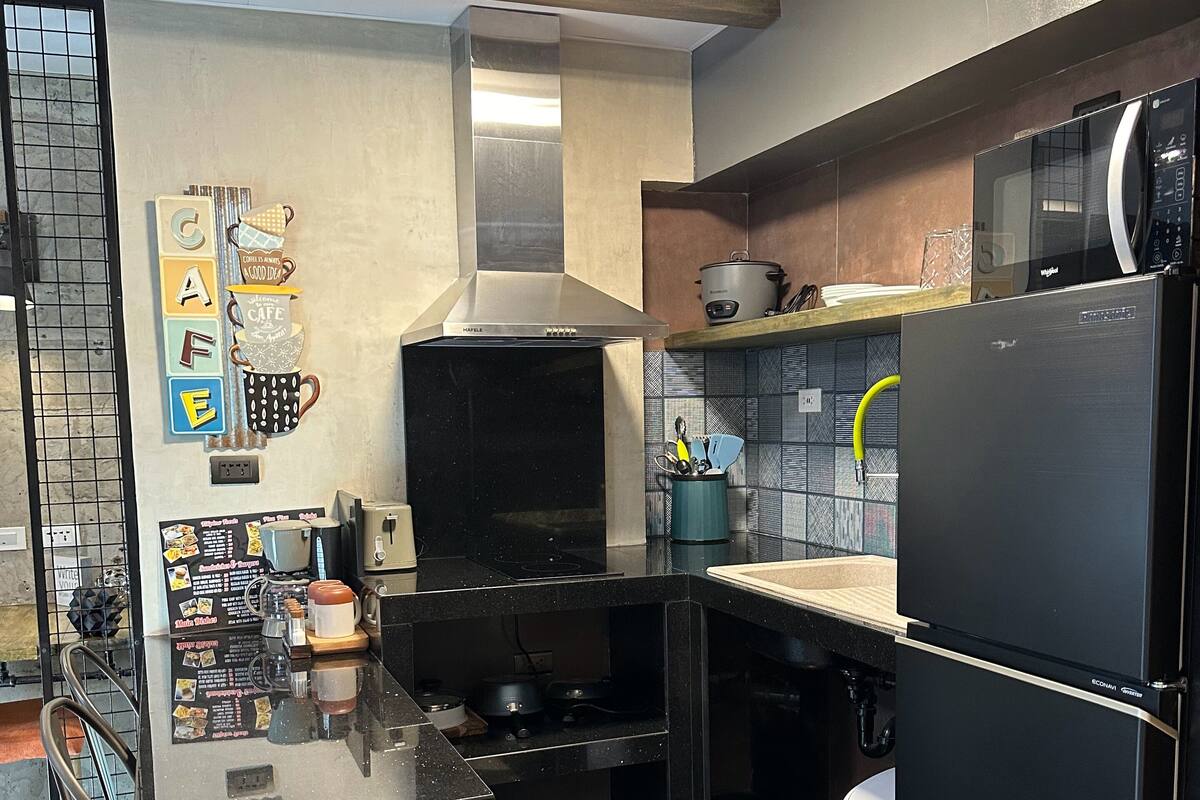 A modern kitchen with a black countertop, stainless steel appliances, a built-in oven, and a microwave.