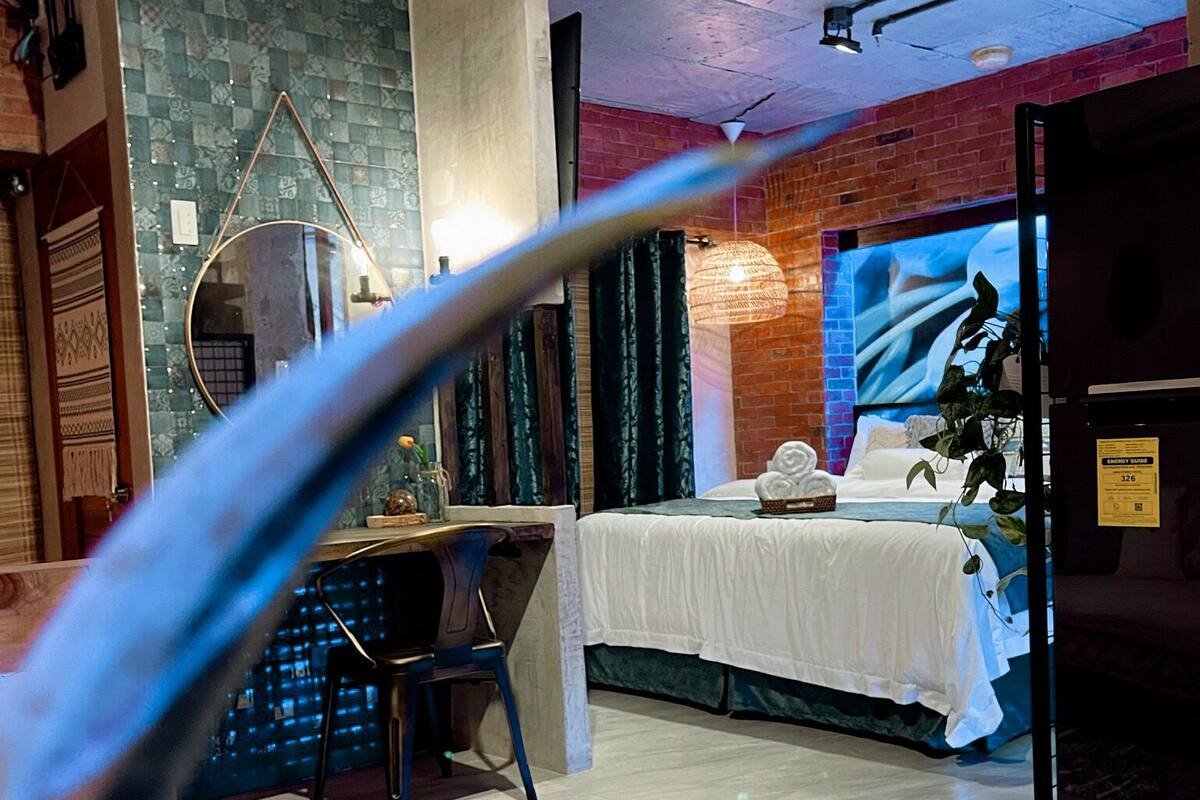 A modern hotel room with a bed, a desk, and a large window.