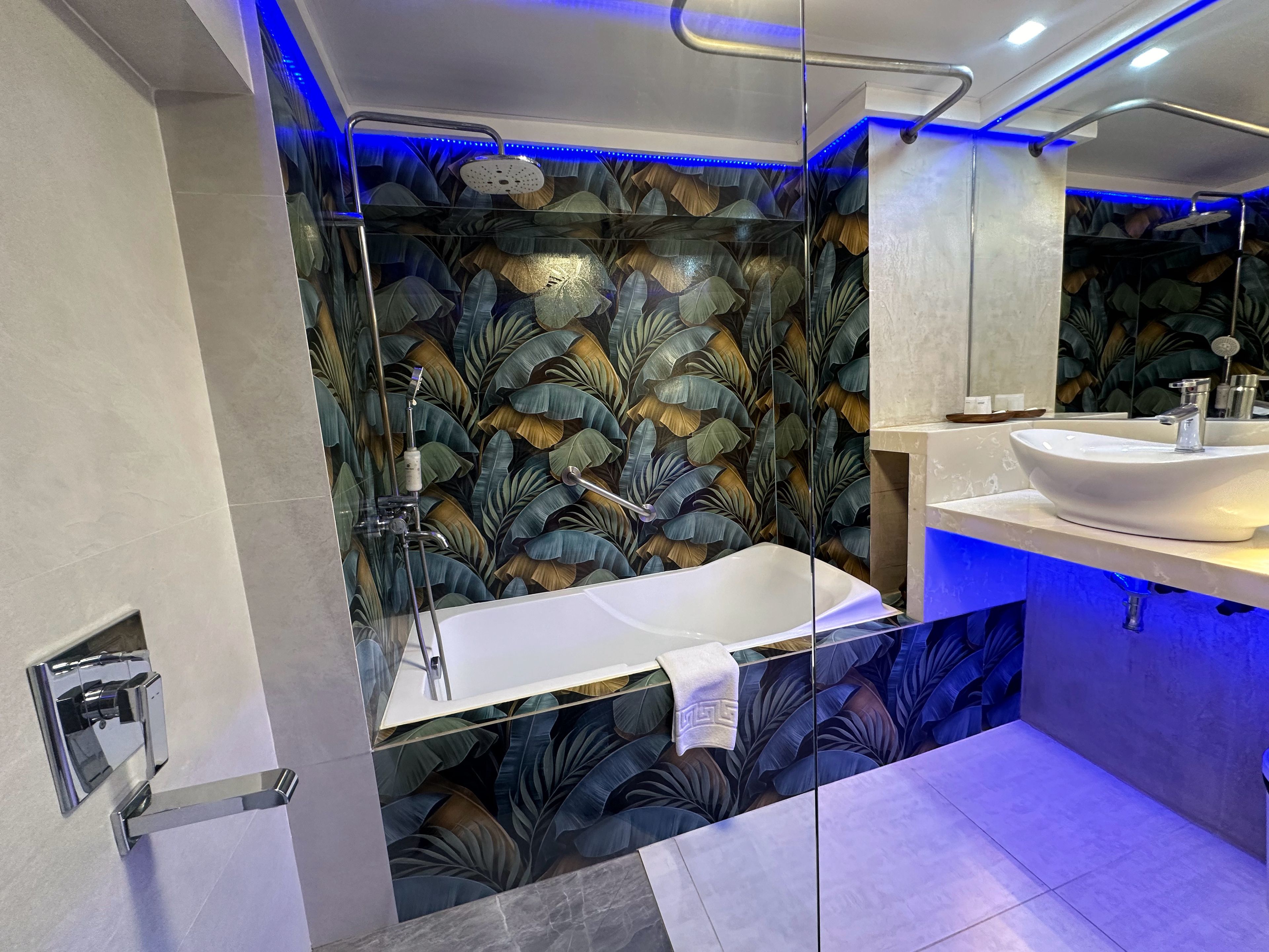 Un baño moderno con ducha envuelta en vidrio, una bañera blanca y un tocador con espejo.