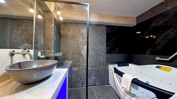 Un baño moderno con cabina de ducha de vidrio, un lavamanos grande tipo recipiente y una bañera blanca.