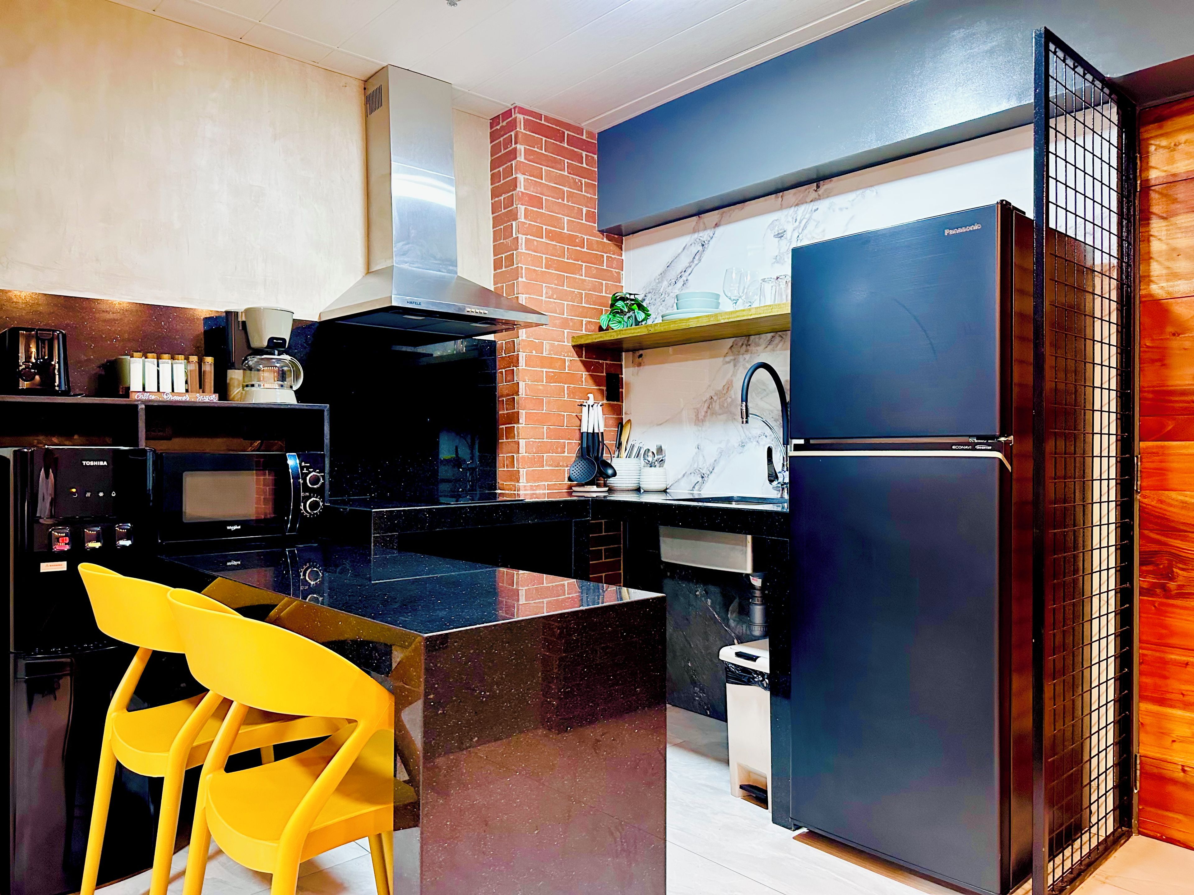Una cocina moderna con un refrigerador negro, un microondas y un lavamanos.