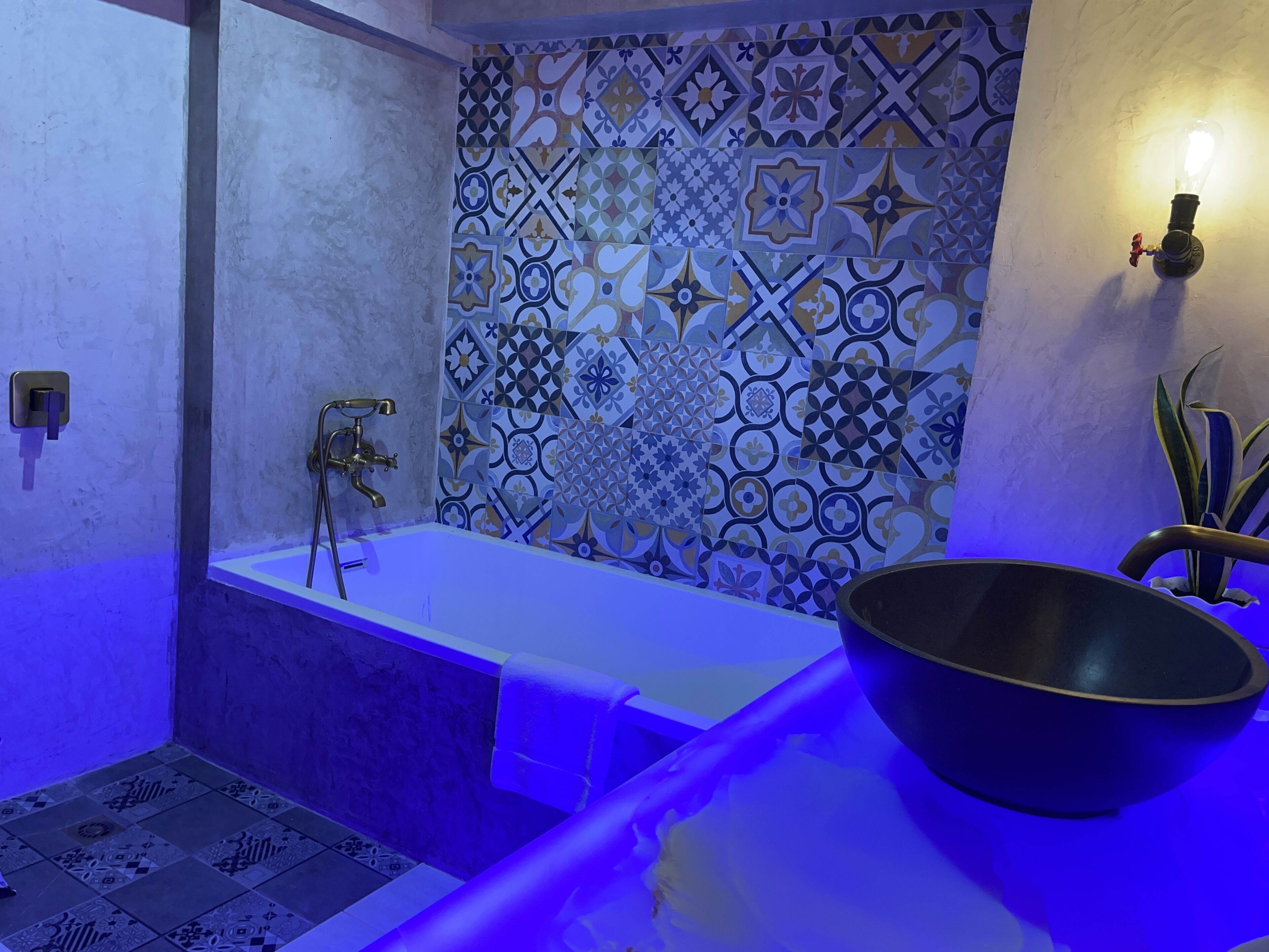 Uma casa de banho com banheira, lavatório e parede decorativa com azulejos estampados.