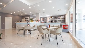 Um saguão moderno de hotel com área de bar, assentos e vista para a rua.