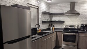A modern kitchen with a stainless steel refrigerator, a built-in oven, and a microwave.