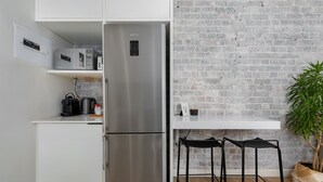 A compact kitchen with a stainless steel refrigerator, a coffee maker, and a white countertop. - Luxurious Studio Apartment | Netflix | Wifi (Cape Town)