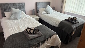 Une chambre d’hôtel avec deux lits, chacun doté d’une tête de lit, d’une table de chevet, d’une lampe et d’une fenêtre avec des stores.