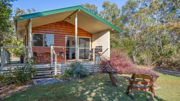 Eine Holzhütte mit Veranda, großen Fenstern und einer überdachten Sitzgruppe im Freien.