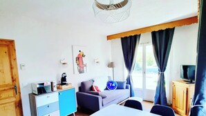 A compact living space with a kitchenette, a dining table, a sofa, and a television.