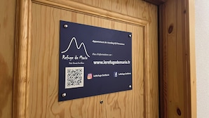 A wooden door with a sign indicating it is a 4/6 person apartment, including a QR code and social media icons.