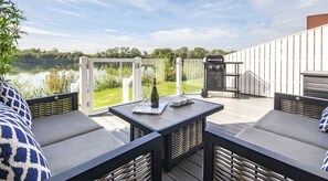 An outdoor deck with a table, chairs, and a grill.