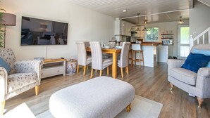 A modern living room with a dining area, kitchen, and a staircase leading to another level. - Spring Lake 14, Lakeside Retreat - Waterside Lodge, Watersports, Sleeps 6 (South Cerney)