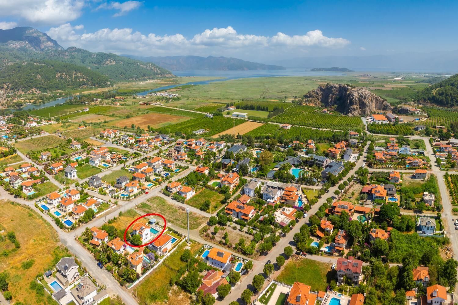Vue aérienne d’un quartier résidentiel avec des maisons, des routes et une grande étendue d’eau en arrière-plan.
