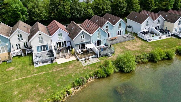 Eine Reihe von Häusern mit Terrassen und ein Fluss im Vordergrund.