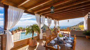 Comedor con vista al mar, vigas de madera y una piscina.