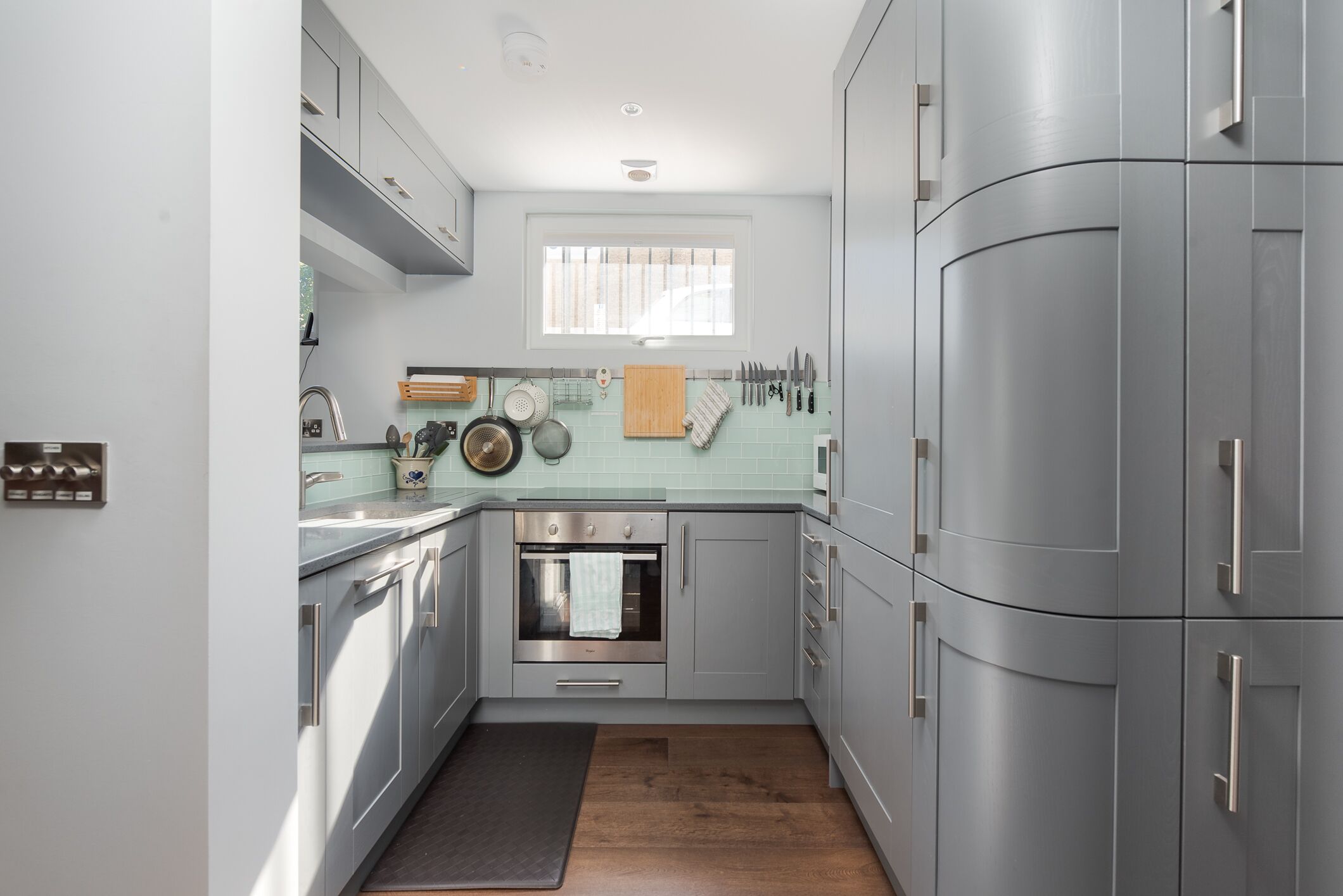 Una cocina moderna con electrodomésticos de acero inoxidable, azulejos azul claro y suelo de madera.