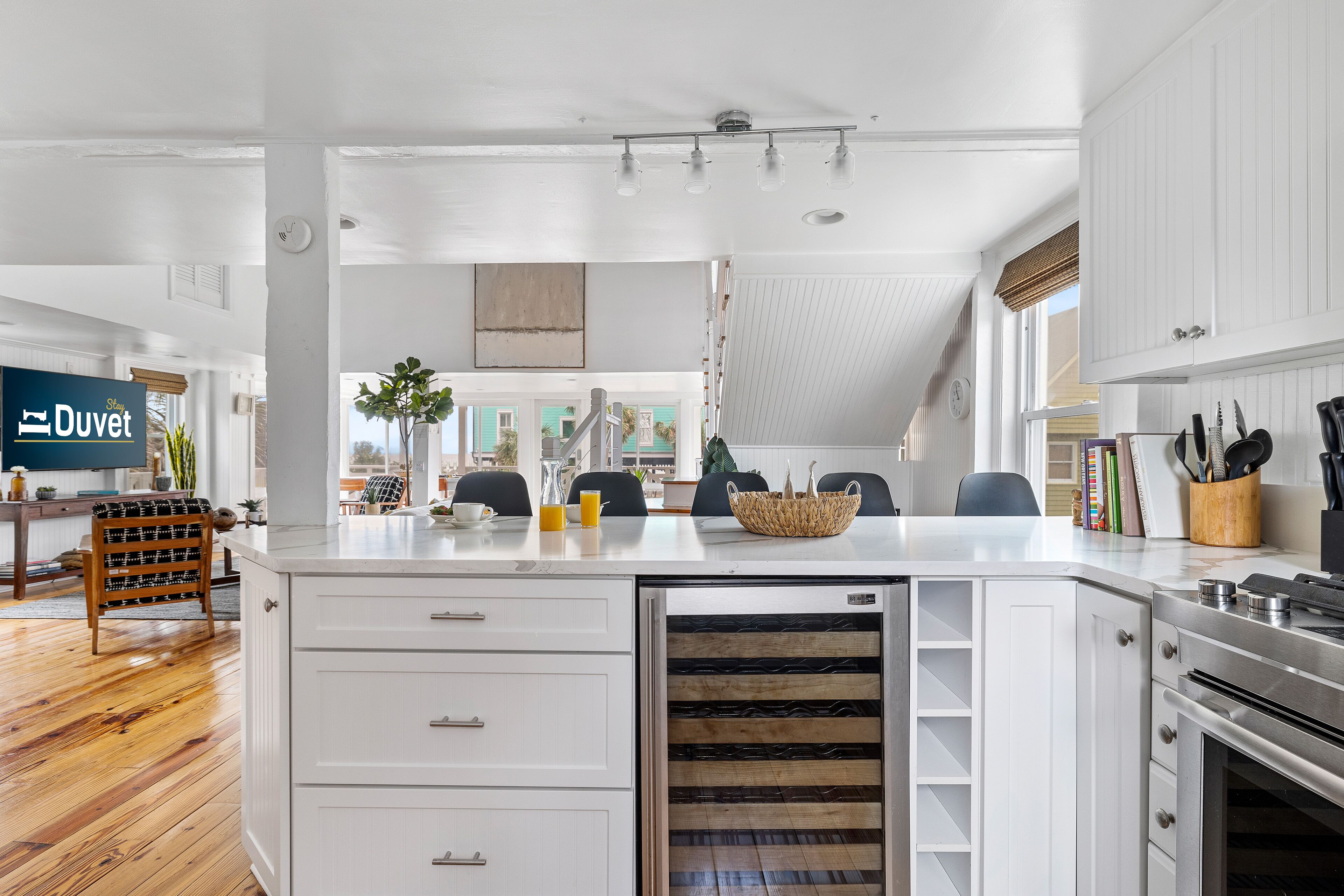 A modern kitchen with white cabinetry, a built-in oven, and a large island with a wine cooler.