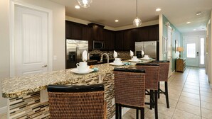 A modern kitchen with granite countertops, dark cabinetry, and a central island with bar stools. - Encore Resort 11 Bedroom Home with Pool (2206) (Kissimmee)