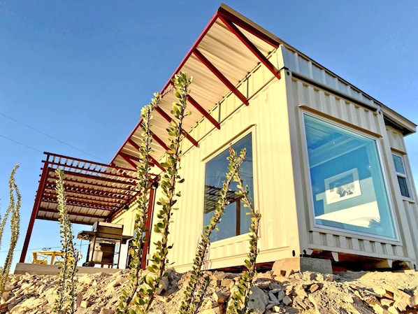 A modern building with a large window, a metal roof, and a stone foundation.