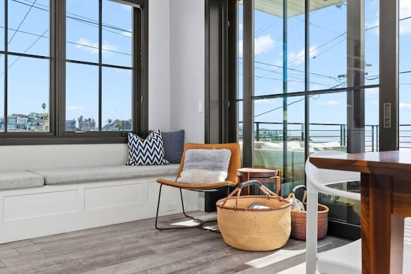 A modern room with large windows, a cushioned bench, a chair, and a table.
