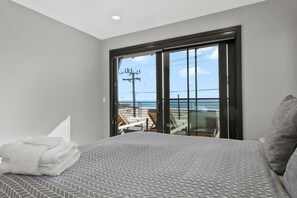 A hotel room with a bed, a view of the beach, and a balcony with chairs. - Luxury Twin Lakes Beachhouse (Santa Cruz)