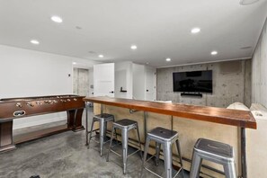 A modern bar area with a pool table, stools, and a television mounted on the wall. - Luxury Twin Lakes Beachhouse (Santa Cruz)