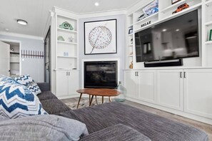 A modern living room with a grey sofa, a TV, and a fireplace.