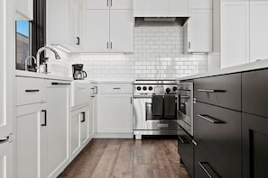 Een moderne keuken met witte kasten, een roestvrijstalen fornuis en een houten vloer.