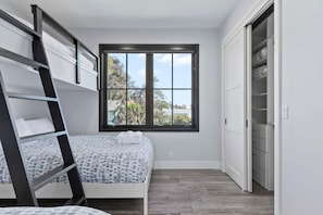 Une chambre avec un lit superposé, une fenêtre donnant sur un beau paysage et un placard.