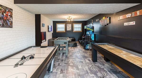 Une salle équipée de tables de baby-foot, d’une table de billard et d’un espace dédié au jeu de shuffleboard.