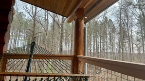 Eine Holzterrasse mit einer Hängematte und Blick auf einen Wald.