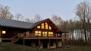 Eine Holzhütte mit Balkon und großen Fenstern, umgeben von Bäumen.