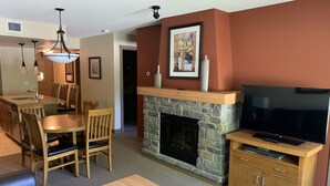 Una sala de estar con chimenea, televisor y comedor con sillas y una mesa.