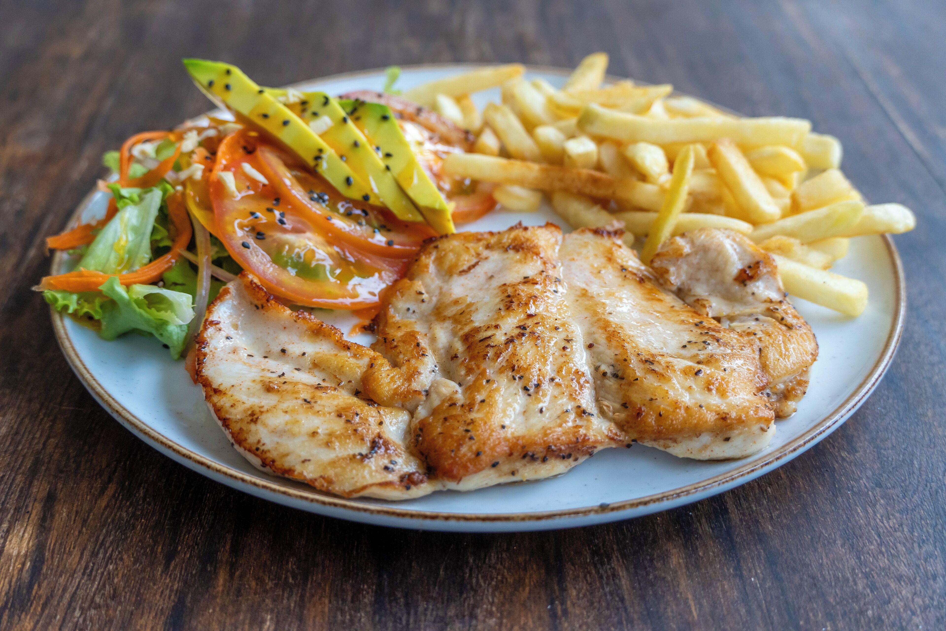 A plate with grilled fish, French fries, and a salad.
