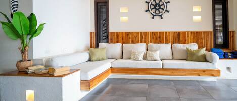 A modern living room with a white sectional sofa, wooden headboard, and a ship's wheel wall decoration.