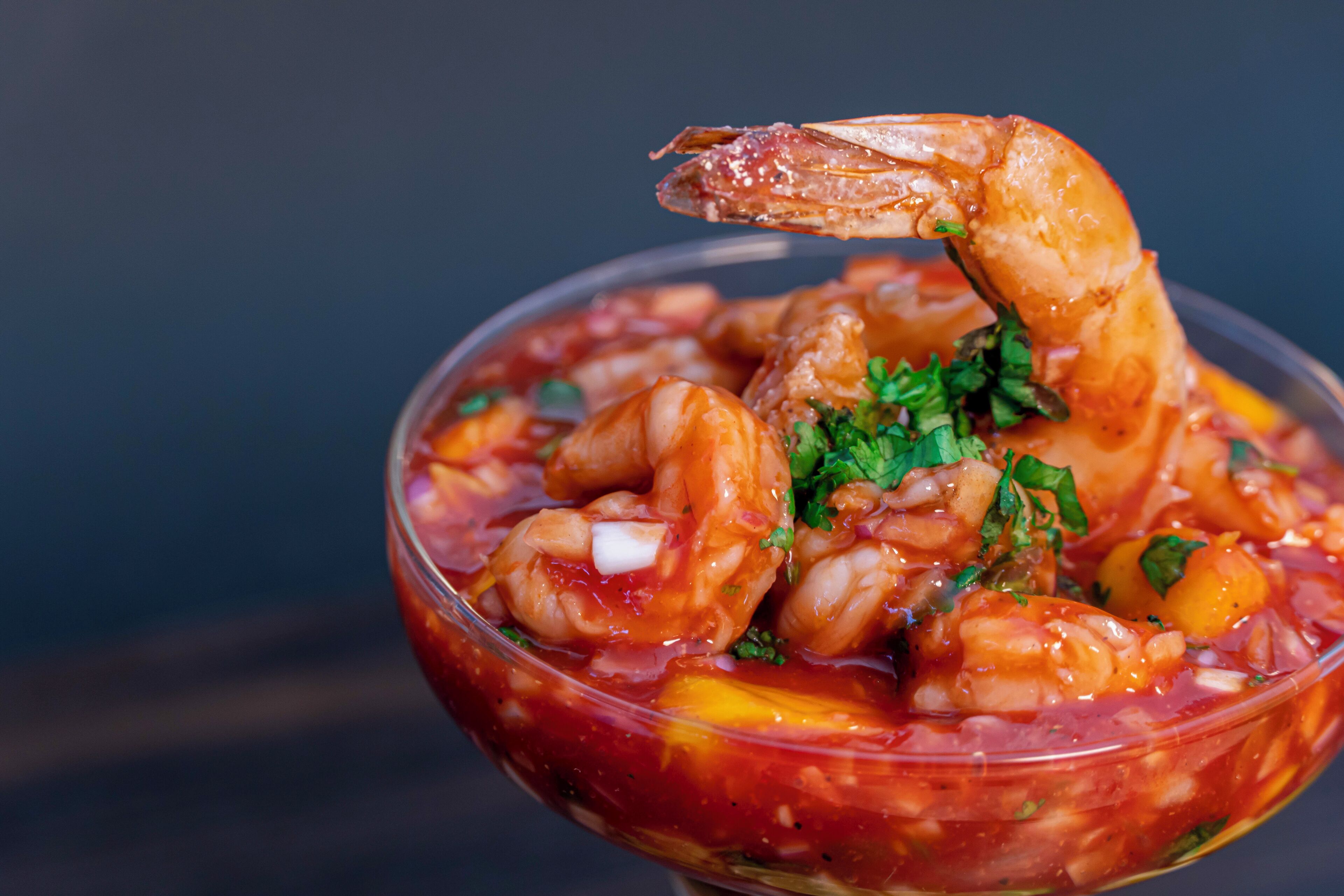 A bowl of seafood stew with shrimp and herbs.