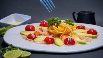 A plate of pasta with cherry tomatoes, avocado, and cheese.