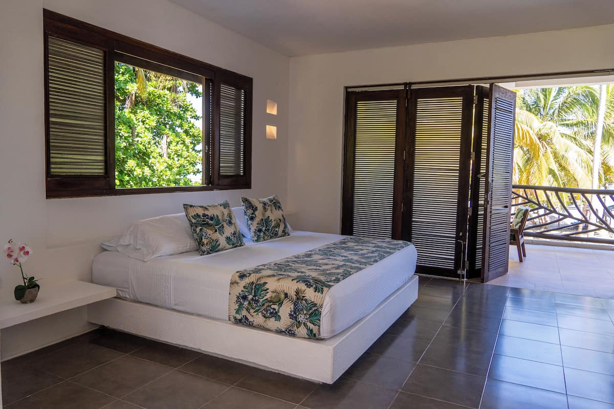 Un dormitorio con cama, mesita de noche y ventana con persianas.