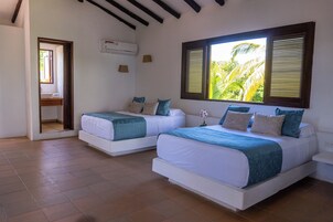 Una habitación con dos camas, una ventana con persianas, una puerta y un equipo de aire acondicionado.