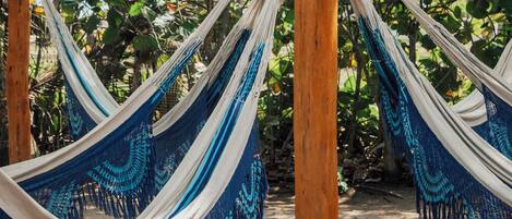 A hammock set up between wooden posts in a natural setting with dense foliage in the background.