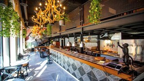 A modern bar area with a patterned countertop, hanging plants, and pendant lighting. - Hotel Philosophy (Amman)