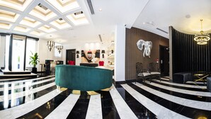 Eine moderne Lobby mit einem türkisblauen Sofa, einem schwarz-weißen Streifenboden und einer großen Kronleuchter.
