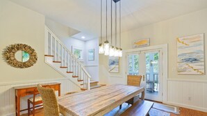 A dining area with a wooden table, benches, wicker chairs, and a staircase leading to another room. - 5 Mins to Seaside Beach, Prime Location, Amazing Porches + 2 Adult Bikes! (Santa Rosa Beach)
