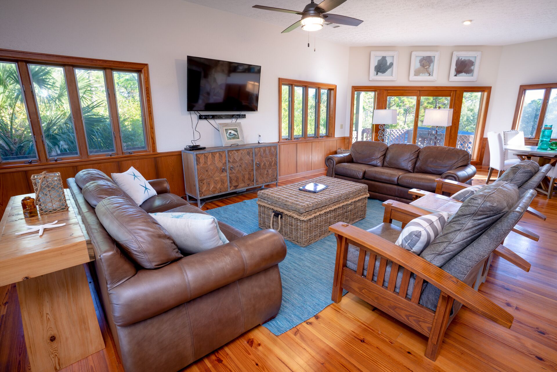 A spacious living room with leather sofas, a wooden coffee table, and a television mounted on the wall.