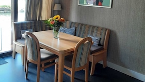 A dining area with a wooden table and chairs, a bench, a vase with flowers, and a painting on the wall. - Central, cosy and modern appartment in Houseboat. Amsterdam Pur Sang. (Amsterdam)