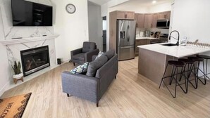 Een moderne keuken met een centraal eiland, inbouwapparatuur en een eethoek met barkrukken.