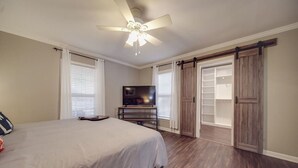 Ein Schlafzimmer mit einem Bett, einem Fernseher, einem Schreibtisch und einem Kleiderschrank mit Schiebetüren.