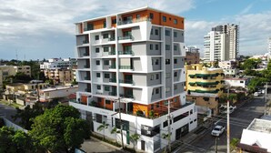 A multi-story building with balconies, surrounded by other buildings and trees. - Brand New luxury condo in Alma Rosa 1, large terrace (Santo Domingo Este)