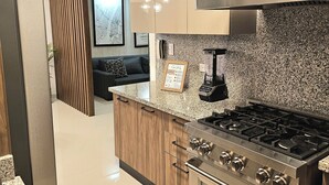 A modern kitchen with a stainless steel stove, wooden cabinets, and a granite countertop. - Brand New luxury condo in Alma Rosa 1, large terrace (Santo Domingo Este)