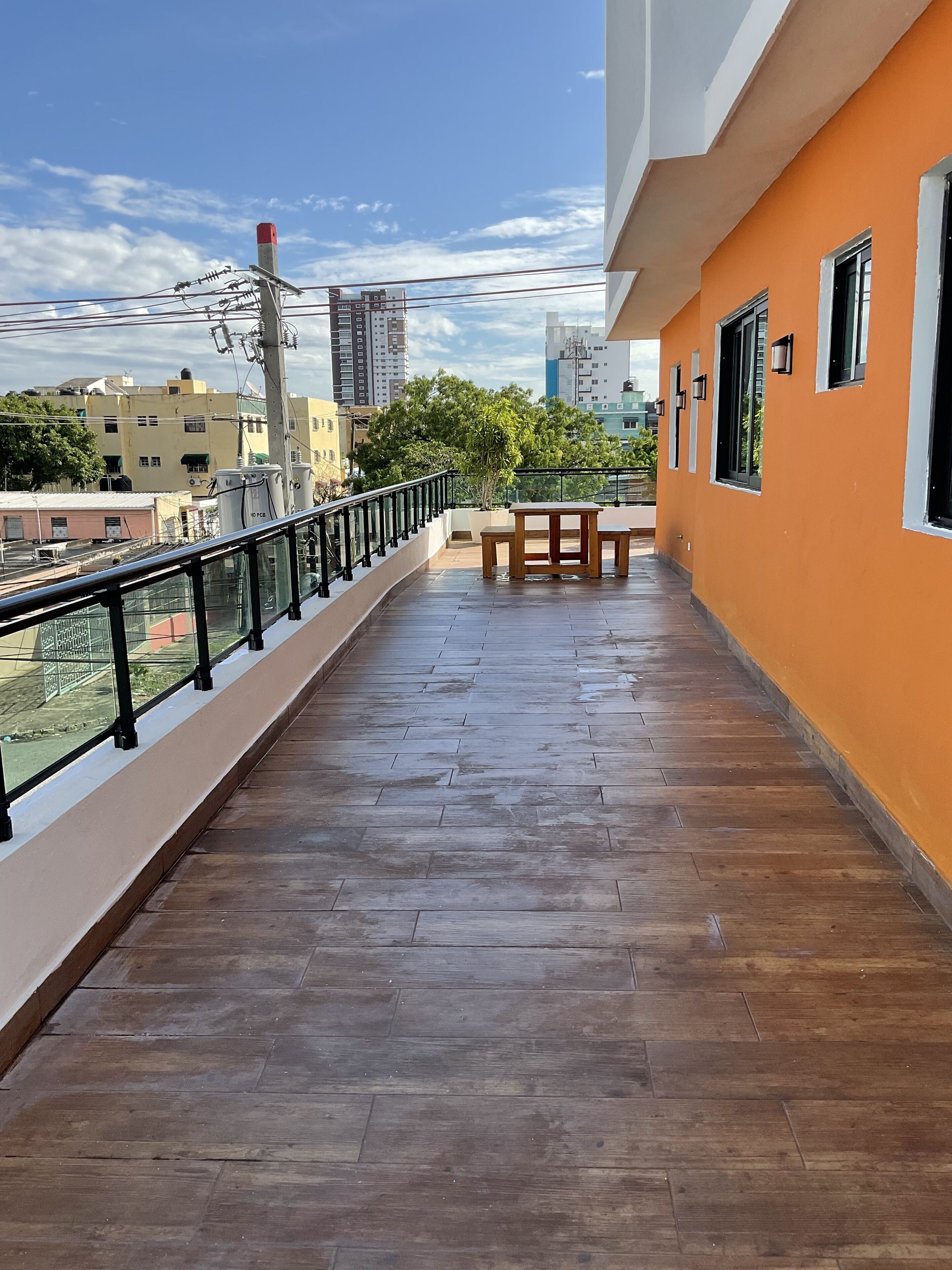 Ein Balkon mit Holzboden, einer Bank und einem Geländer.